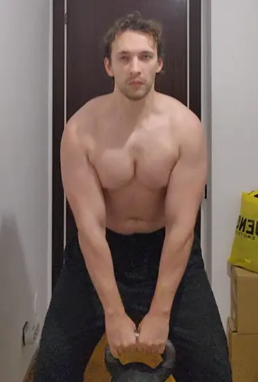 Doing kettlebell swings at home, demonstrating proper form and explosive movement